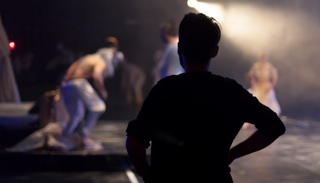 director standing watching theater play