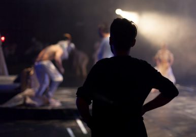 director standing watching theater play